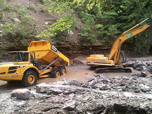 Heavy equipment (dump truck and digger) working to restore stream habitat